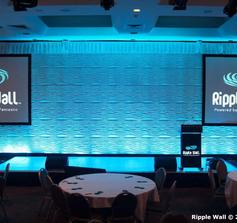 A conference room setup features two projection screens displaying 