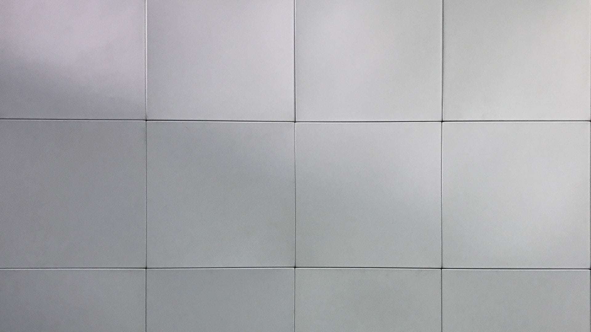 A grid of evenly spaced, square, light gray tiles forming a flat wall creates the perfect modular backdrop.