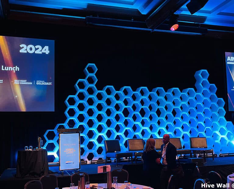 Room with Hive Modular Panel backdrop, stage set with screens displaying