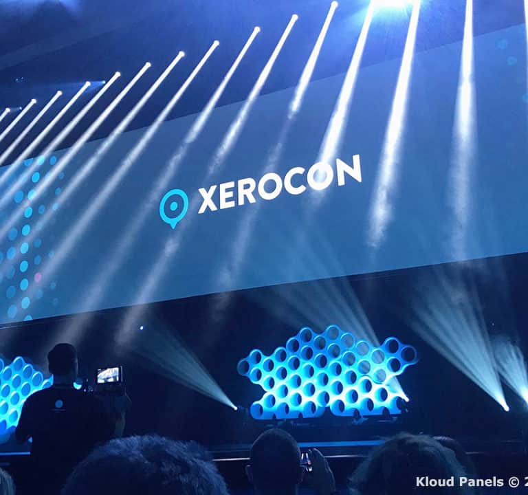 A stage set with blue lighting and a large screen displaying the logo 