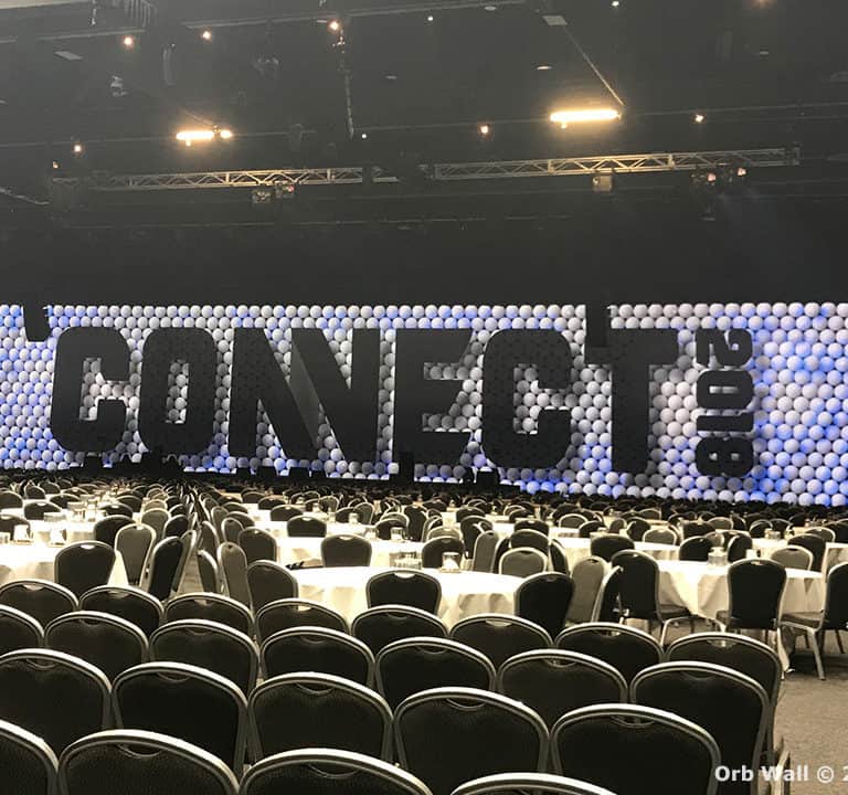 A large event hall with a balloon backdrop spelling 
