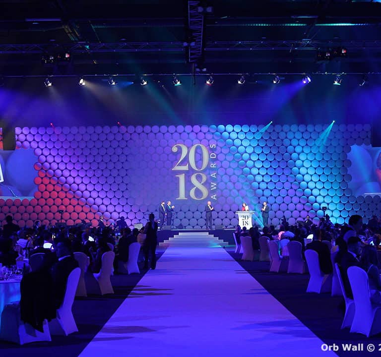 A large event hall with a central stage displays the year 